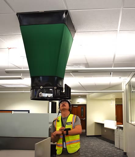 A TAB Services technician measuring airflow with a capture hood